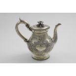 A GEORGE III EMBOSSED TEA POT with a baluster body, a c-scroll handle and a flower finial,