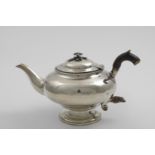 A GEORGE IV TEA POT with a compressed circular body, circular pedestal foot and a flower finial (the