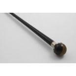 A LATE VICTORIAN BLACK-LACQUERED WALKING CANE with a mounted tiger's eye, ball finial or handle,