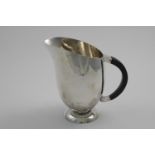 A WW2 PERIOD HANDMADE WATER EWER OR PITCHER helmet-shaped with a domed foot & a hammered finish,