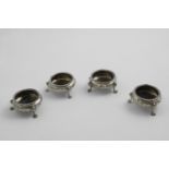 A SET OF FOUR VICTORIAN SQUAT CIRCULAR SALTS on three fluted paw feet, with embossed decoration