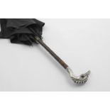 AN EARLY 20TH CENTURY BLACK SILK UMBRELLA with a mounted cane shaft and a bird mask handle, set with