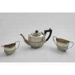AN EDWARDIAN THREE-PIECE TEA SET with part-fluted oval bodies and angular handles, by William