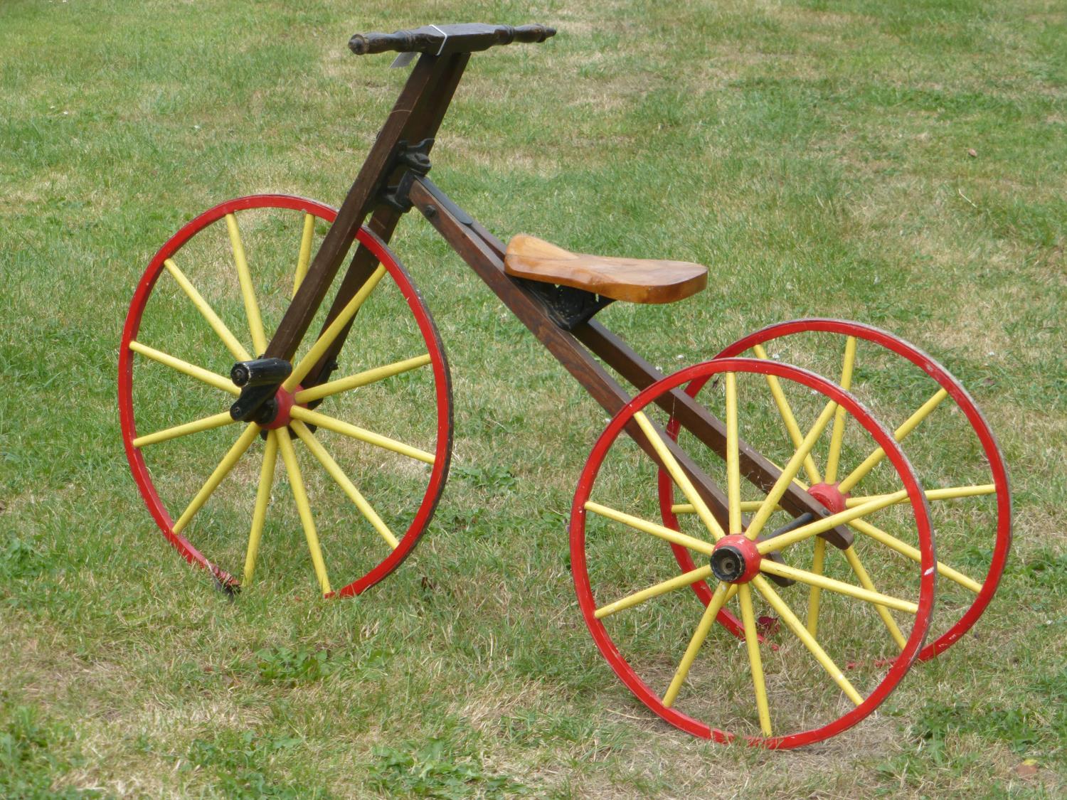 A Child's Wooden-Framed Vélocipède. A tricycle with a 25-inch steering and driving wheel, wooden