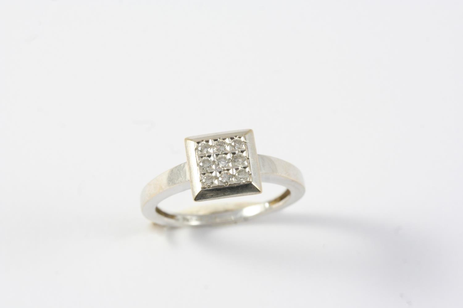 A DIAMOND PLAQUE RING mounted with nine circular-cut diamonds, in 18ct white gold. Size N 1/2