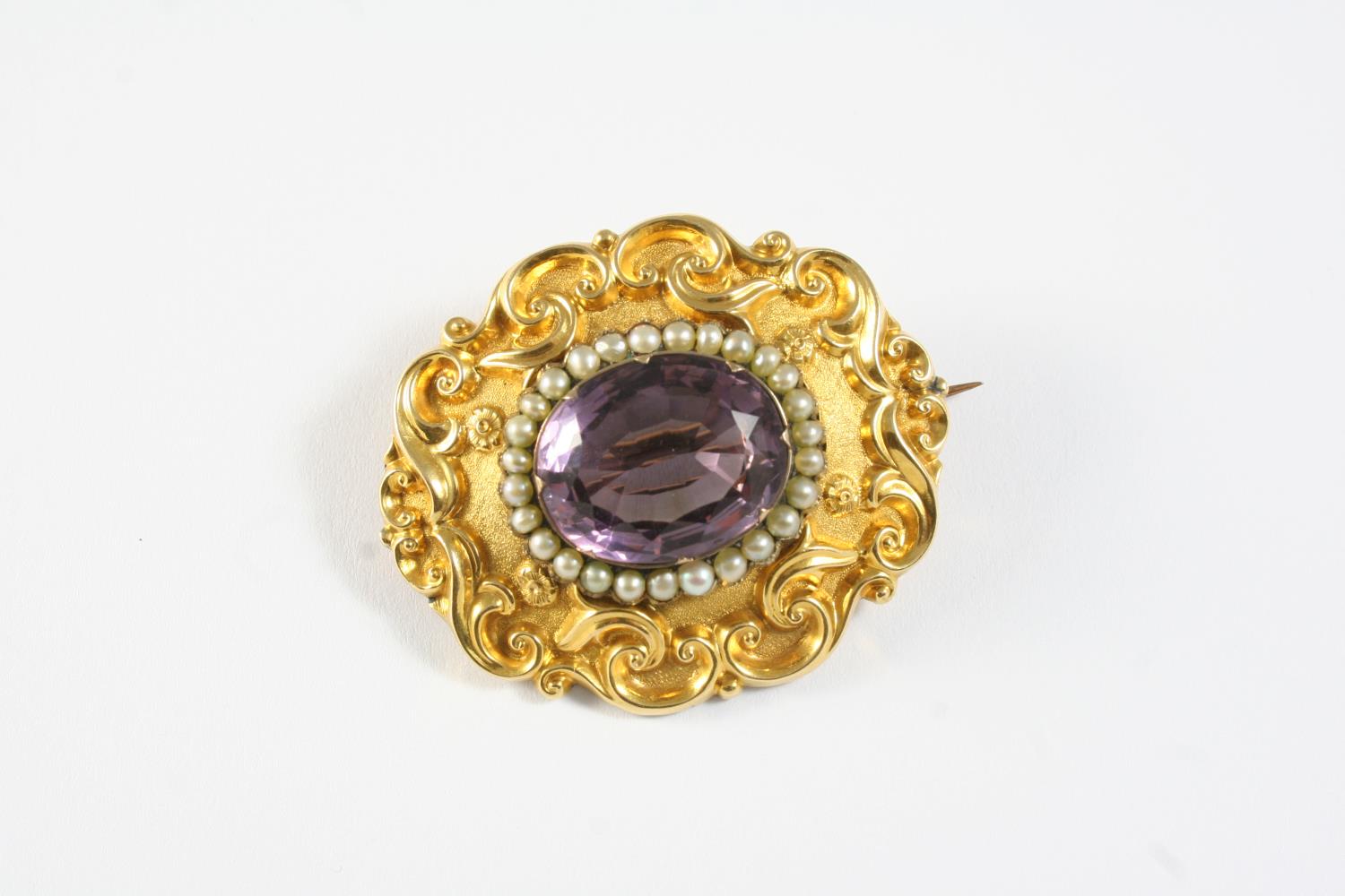 A VICTORIAN GOLD, AMETHYST AND PEARL SET BROOCH the oval-shaped amethyst is set within a surround of