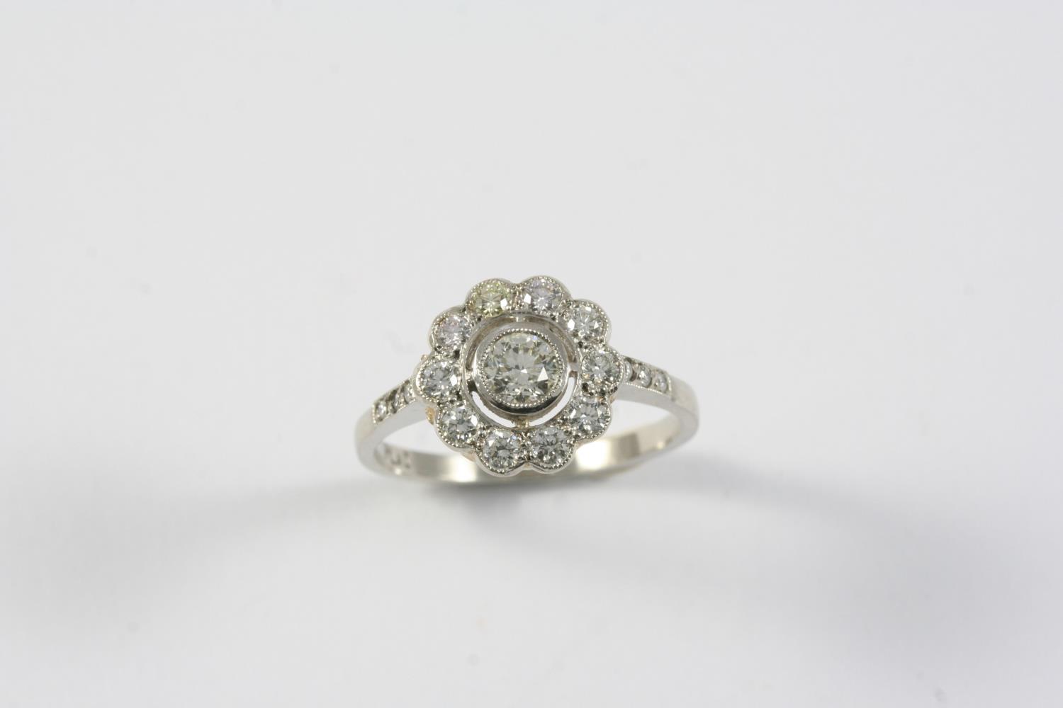 A DIAMOND CLUSTER RING the flowerhead design is set with circular-cut diamonds, in platinum. Size O