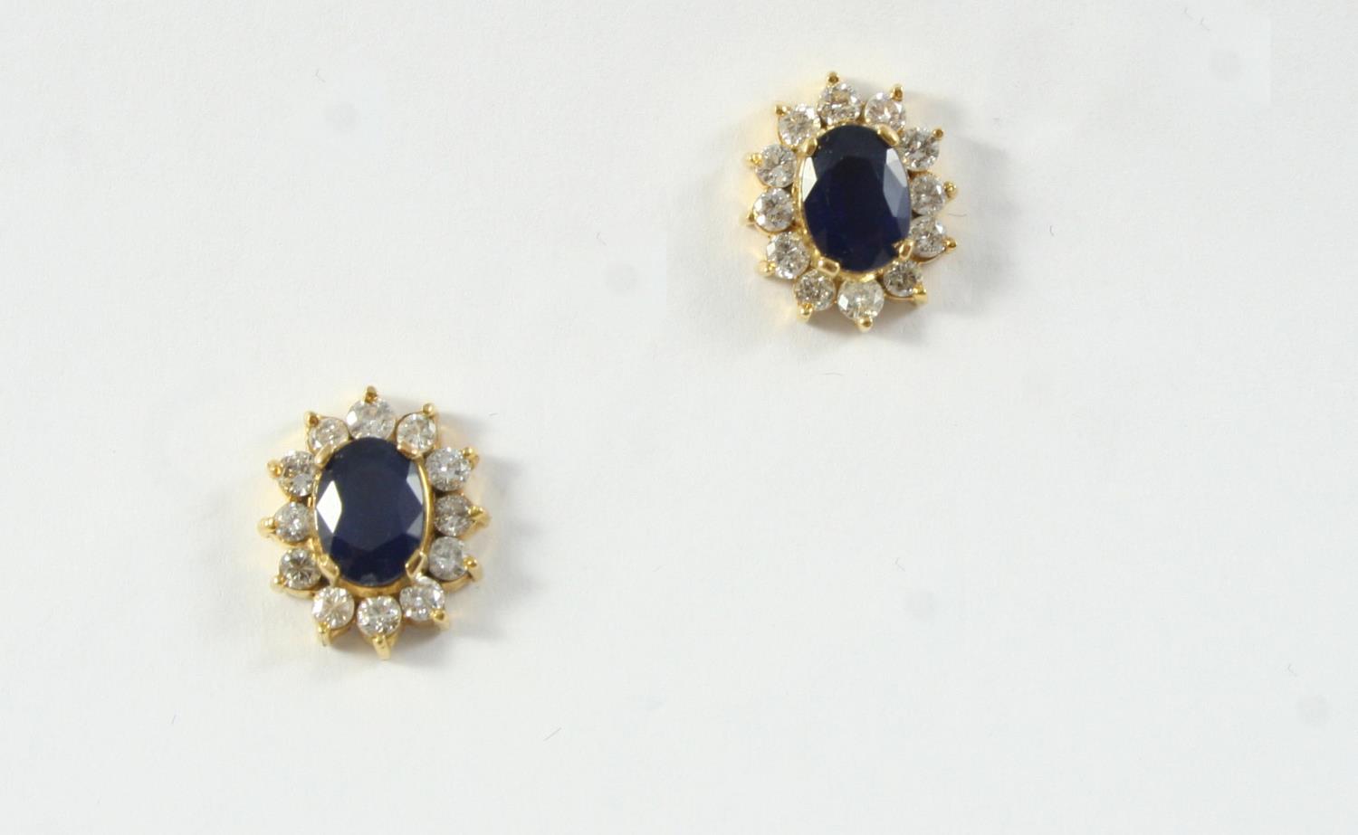 A PAIR OF SAPPHIRE AND DIAMOND CLUSTER STUD EARRINGS each earring set with an oval-shaped sapphire