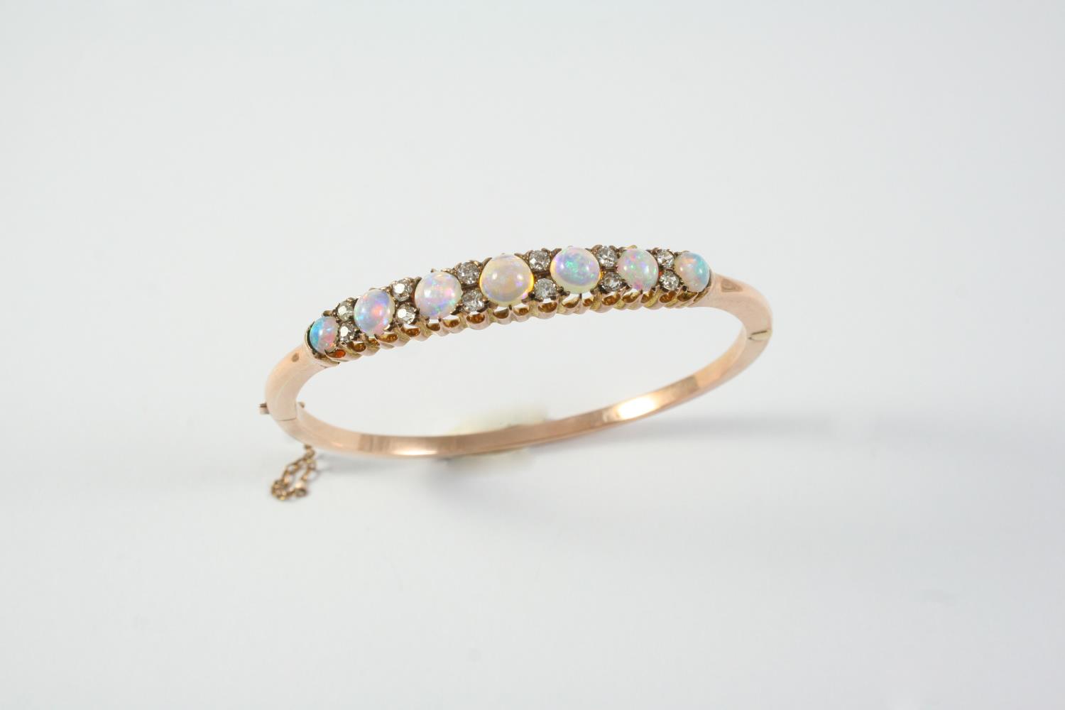 AN EARLY 20TH CENTURY OPAL AND DIAMOND HALF HINGED BANGLE mounted with seven graduated circular