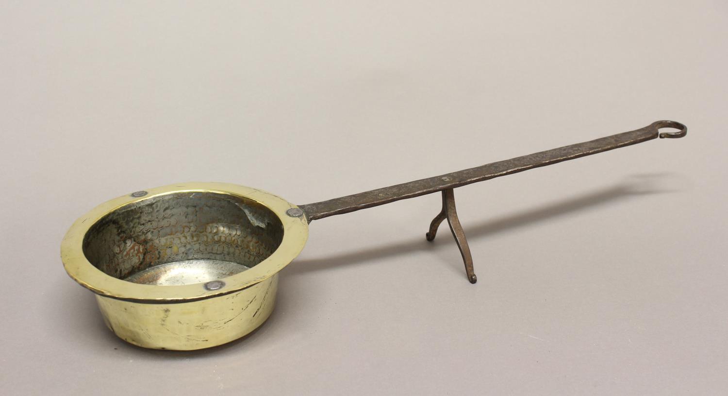 A LATE 18TH IRON AND BRASS DOWNHEARTH SAUCEPAN. A circular brass saucepan with a long iron handle