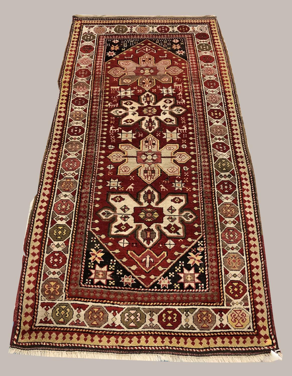 A KARABAGH RUG, the blood red field with four cruciform medallions flanked by tribal devices