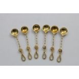 A SET OF SIX VICTORIAN SILVERGILT SALT SPOONS with chased whip ends, shell bowls and twist stems, by