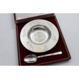 A GEORGE V CHILD'S DISH AND SPOON with engraved figures from Peter Pan, the back of the bowl with