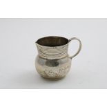 A GEORGE V SMALL HANDMADE CREAM JUG with a bellied body, reeded neck and loop handle, by Theodore