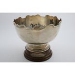 A GEORGE V CIRCULAR ROSE BOWL with a shaped and moulded rim and acoompanying turned wooden plinth