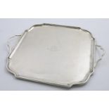 A GEORGE V TWO-HANDLED TRAY of shaped square outline with a plain moulded border, engraved in the