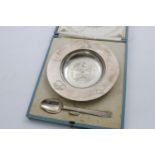 A GEORGE VI CHILD'S DISH AND SPOON with engraved decoration: a cow, a milkmaid, sacks of malt, a