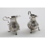 A GEORGE II BALUSTER CREAM JUG on three legs with repousse decoration, engraved initial "M" and