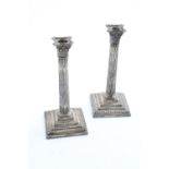 A PAIR OF LATE VICTORIAN CANDLESTICKS on stepped and beaded square bases with fluted columns and