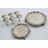 AN EDWARDIAN SMALL SALVER of shaped circular outline with a shell & scroll border and scroll feet,