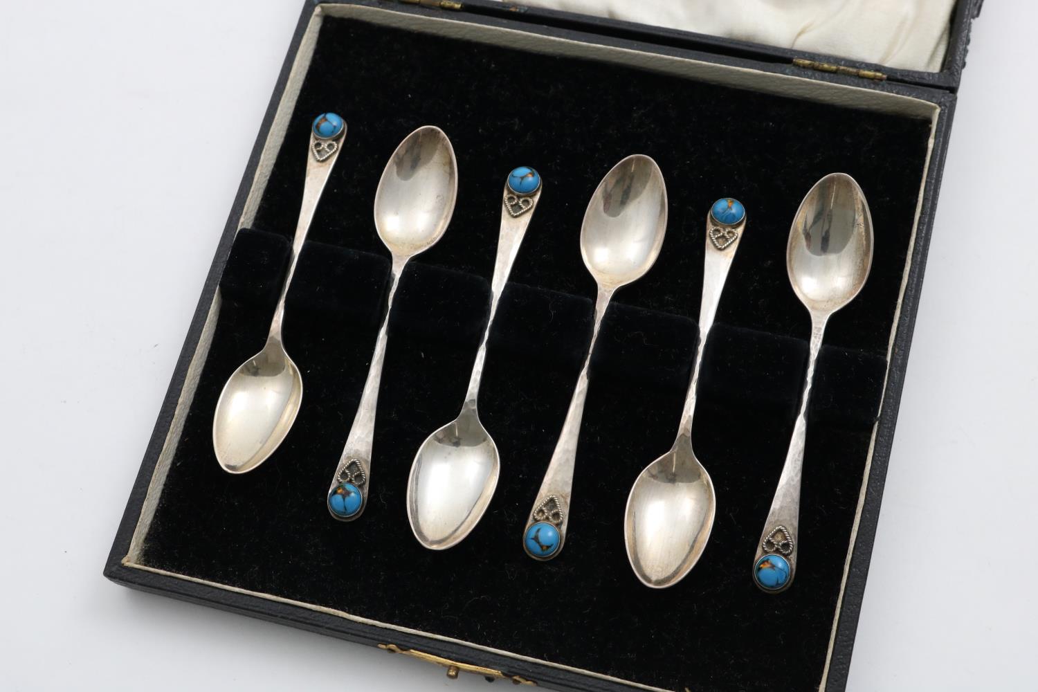 A CASED SET OF SIX GEORGE V HANDMADE COFFEE SPOONS with a hammered finish, the terminals with an