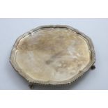 A GEORGE V SALVER of shaped circular outline with a gadrooned border and ball & claw feet, by