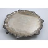 A GEORGE V SALVER of shaped circular outline with a husk and scroll border, the centre with an
