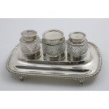 A GEORGE III INKSTAND of rounded oblong form with a gadrooned border, paw feet and three mounted