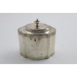 A GEORGE III TEA CADDY with an oval, serpentine outline, engraved borders and a knop finial, the
