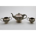 AN EARLY 20TH CENTURY INDIAN THREE-PIECE TEA SET with embossed circular bodies and elephant-mask