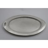 AN EDWARDIAN OVAL TEA TRAY with a broad rim, cut-out handles and a part-fluted border, by Walker &