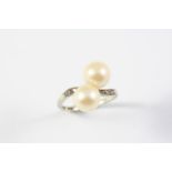 A CULTURED PEARL AND DIAMOND CROSS-OVER RING set with two cultured pearls, with small diamonds to