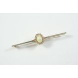 AN OPAL AND DIAMOND CLUSTER BROOCH the oval-shaped solid white opal is set within a surround of