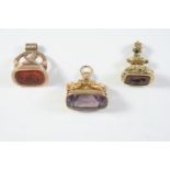 THREE ASSORTED GOLD SEALS one with carnelian matrix engraved with initials, 3cm high, one with