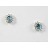 A PAIR OF BLUE TOPAZ AND DIAMOND STUD EARRINGS each earring set with an oval-shaped blue topaz