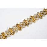 A GOLD PANEL BRACELET formed alternately with gold panels mounted with foliate and shell decoration,