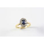 A SAPPHIRE AND DIAMOND CLUSTER RING the oval-shaped sapphire is set within a surround of circular-