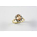 A TOPAZ AND DIAMOND CLUSTER RING the oval-shaped topaz is set within a surround of circular-cut