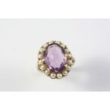 AN AMETHYST AND CULTURED PEARL CLUSTER RING the oval-shaped amethyst is set within a surround of