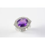 AN AMETHYST AND DIAMOND CLUSTER RING the oval-shaped amethyst is set within a surround of circular-