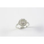 A DIAMOND CLUSTER RING the collet set circular-cut diamond is set within a surround of circular-