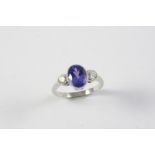 A TANZANITE AND DIAMOND THREE STONE RING the oval-shaped tanzanite is set with two circular-cut