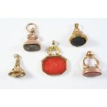 FIVE ASSORTED GOLD SEALS one with a swivel carnelian engraved with a coat of arms, 4.5cm high, one