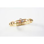 A GOLD, CORAL, PEARL AND DIAMOND HALF HINGED BANGLE the openwork design is centred with a clover