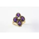 AN AMETHYST AND PEARL QUATREFOIL RING formed with four oval-shaped amethysts centred with a small