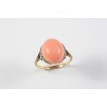 A CORAL AND DIAMOND DIAMOND the oval coral cabochon is mounted with graduated single-cut diamonds to