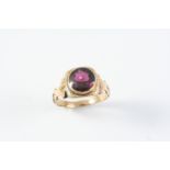 A GARNET SINGLE STONE RING the circular-cut garnet is set in a gold mount with engraved foliate