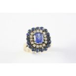 A SAPPHIRE AND DIAMOND CLUSTER RING the oval-shaped sapphire is set within a surround of circular-