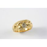 A GOLD AND DIAMOND RING depicting naked female figures holding a diamond ball, 15 grams. Size S