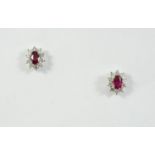 A PAIR OF RUBY AND DIAMOND CLUSTER STUD EARRINGS each earring set with an oval-shaped ruby within